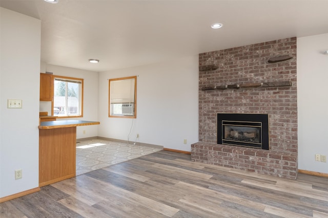 unfurnished living room featuring baseboards, wood finished floors, cooling unit, a fireplace, and recessed lighting