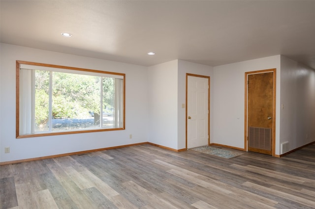 spare room featuring recessed lighting, wood finished floors, visible vents, and baseboards