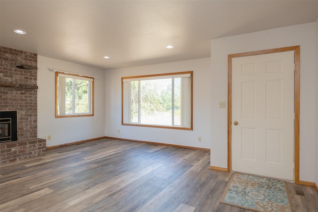 unfurnished living room with a healthy amount of sunlight, a fireplace, and wood finished floors