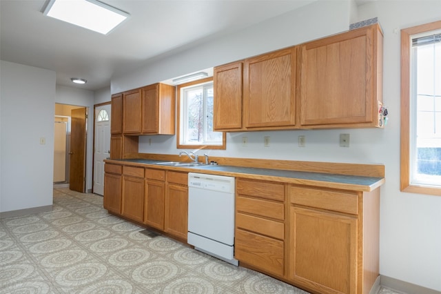 kitchen featuring a wealth of natural light, baseboards, dishwasher, and a sink