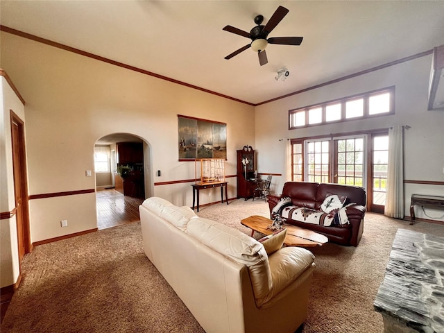 carpeted living room with arched walkways, a healthy amount of sunlight, crown molding, and baseboards