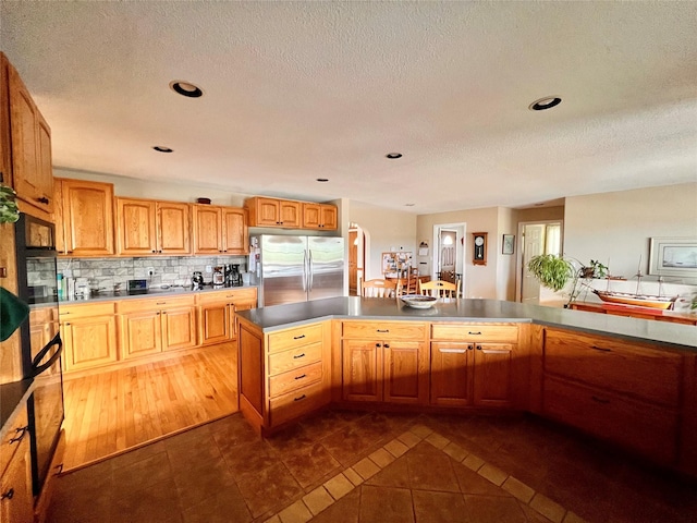 kitchen featuring tasteful backsplash, a textured ceiling, freestanding refrigerator, and dark tile patterned flooring