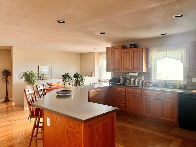 kitchen featuring dishwasher, a breakfast bar area, tasteful backsplash, and a sink