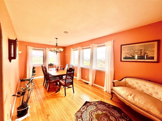 dining room with a notable chandelier, visible vents, baseboards, and light wood-style floors