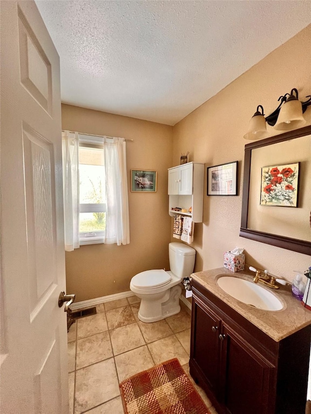 half bath featuring baseboards, toilet, vanity, tile patterned floors, and a textured ceiling