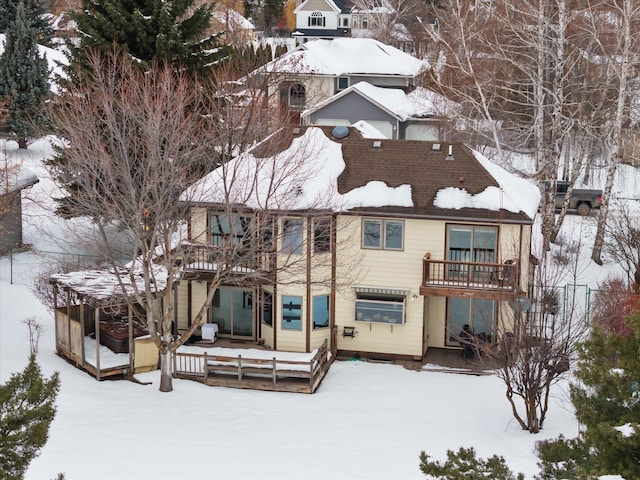 snow covered property with a wooden deck and a balcony