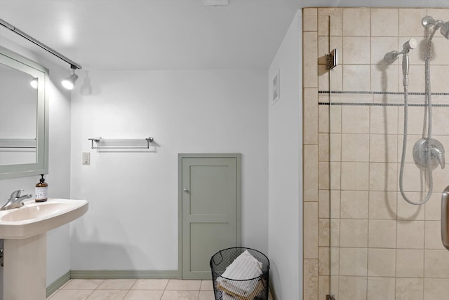 full bath featuring tile patterned flooring, a sink, a shower stall, and baseboards