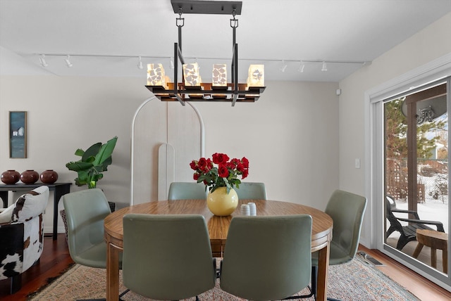 dining room with wood finished floors, rail lighting, and an inviting chandelier