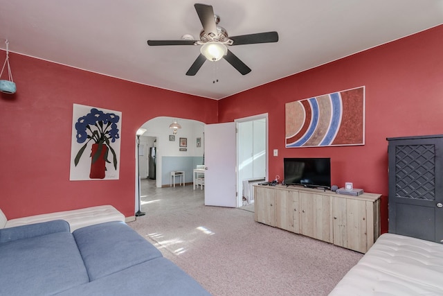 living room featuring carpet floors, arched walkways, and a ceiling fan