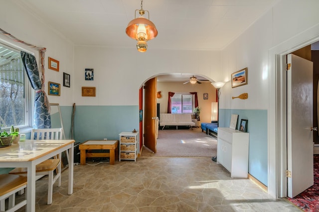 dining area featuring arched walkways, ceiling fan, stone finish floor, and a healthy amount of sunlight