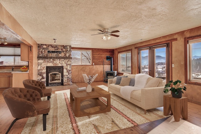 3 Paradise Ridge Rd, Clancy, MT 59634 - living room with light wood-style floors, a textured ceiling, a wood stove, a ceiling fan, and wooden walls