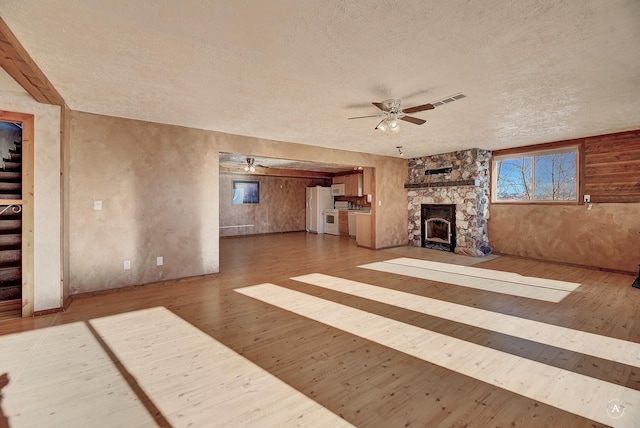3 Paradise Ridge Rd, Clancy, MT 59634 - unfurnished living room featuring a textured ceiling, a ceiling fan, wood finished floors, a stone fireplace, and stairs