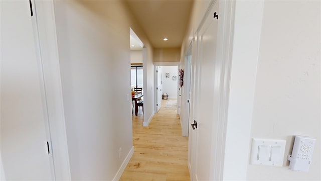 hall with baseboards, recessed lighting, and light wood-style floors