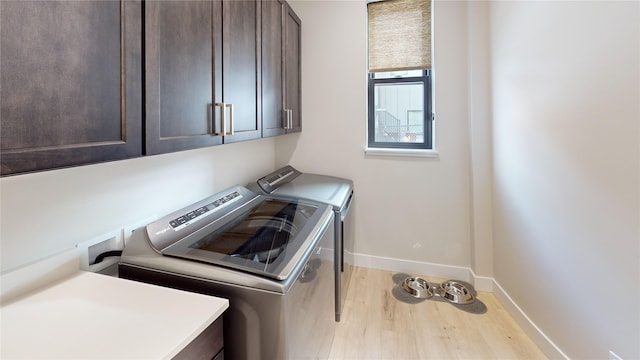 laundry room with baseboards, wood finished floors, cabinet space, and washer and dryer