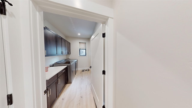 interior space with light wood-type flooring, washing machine and clothes dryer, cabinet space, and baseboards