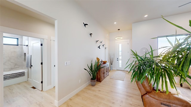 hallway featuring baseboards, recessed lighting, and light wood-style floors