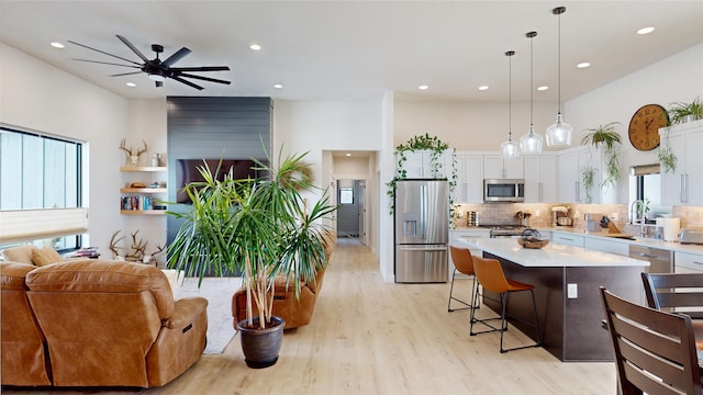 kitchen with stainless steel appliances, a kitchen island, white cabinetry, open floor plan, and decorative backsplash