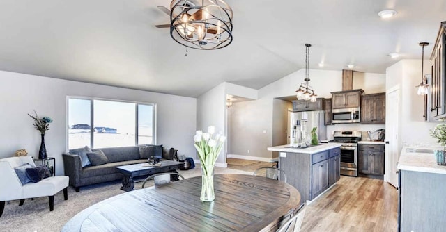 dining space featuring light wood-style floors, lofted ceiling, and baseboards