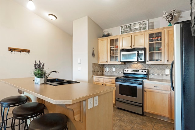 2025 Mullan Rd Unit 409, Missoula, MT 59808 - kitchen with stainless steel appliances, light brown cabinetry, a kitchen breakfast bar, and backsplash