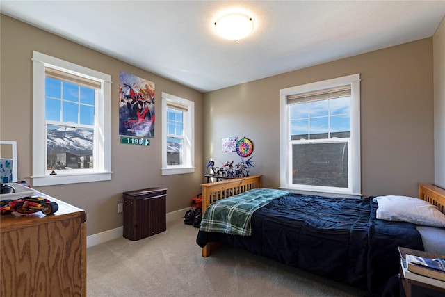 bedroom with light carpet, multiple windows, and baseboards