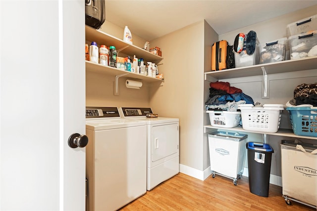 clothes washing area with light wood-style floors, washer and dryer, laundry area, and baseboards