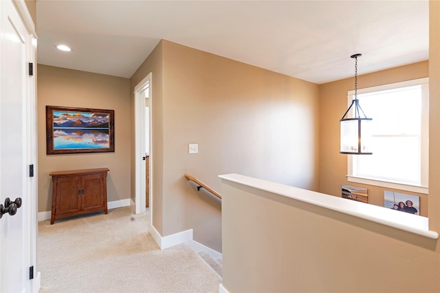 hallway with carpet floors, recessed lighting, baseboards, and an upstairs landing