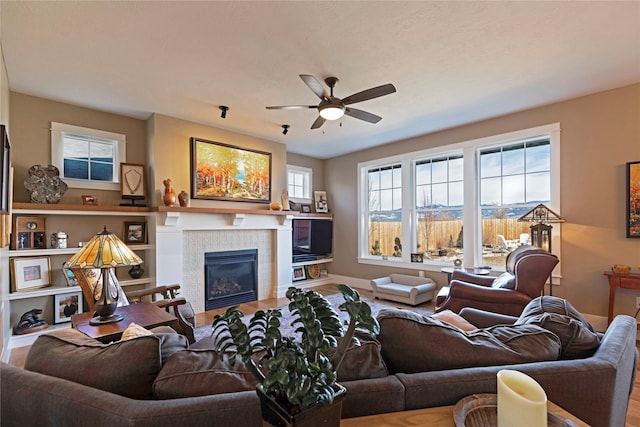 living room with ceiling fan, baseboards, and a tile fireplace