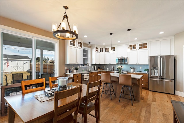 kitchen featuring a center island, stainless steel appliances, light countertops, light wood-style flooring, and white cabinetry