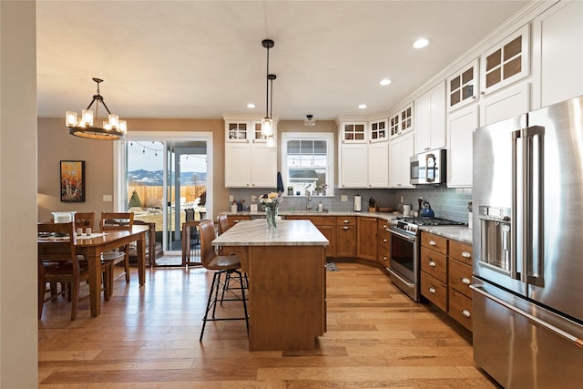 kitchen featuring stainless steel appliances, a kitchen breakfast bar, white cabinets, light wood-type flooring, and decorative backsplash