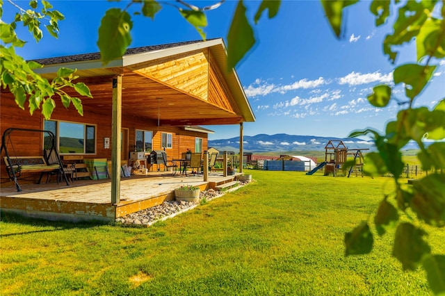view of yard featuring fence, a mountain view, a playground, and a patio area