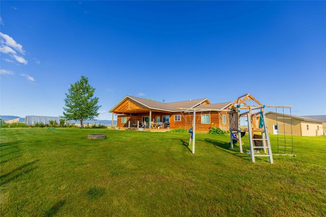 rear view of property with a patio, a playground, and a lawn