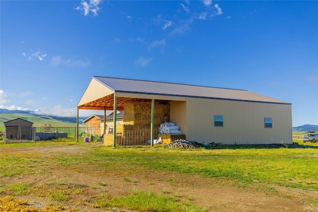 rear view of property featuring a detached carport, fence, an outbuilding, and metal roof