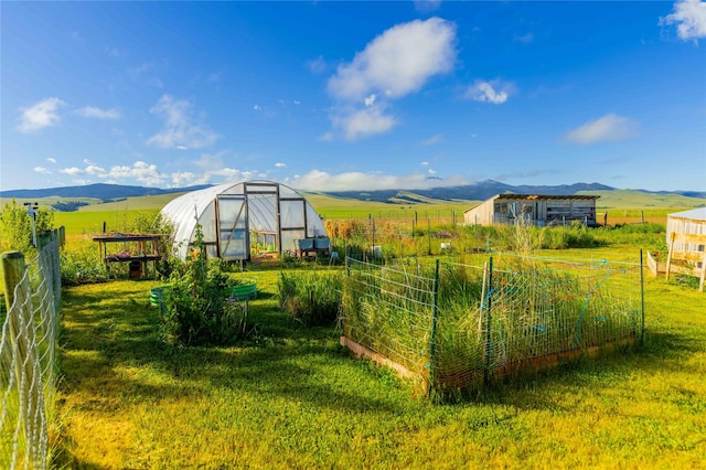 view of yard with an outbuilding, a rural view, a mountain view, fence, and an exterior structure