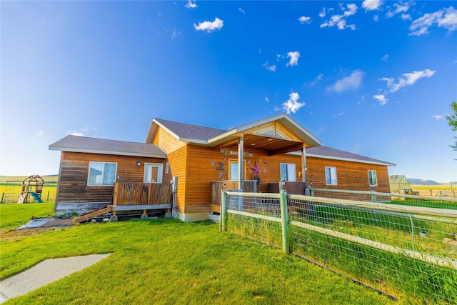 rear view of house featuring a lawn, a playground, and fence