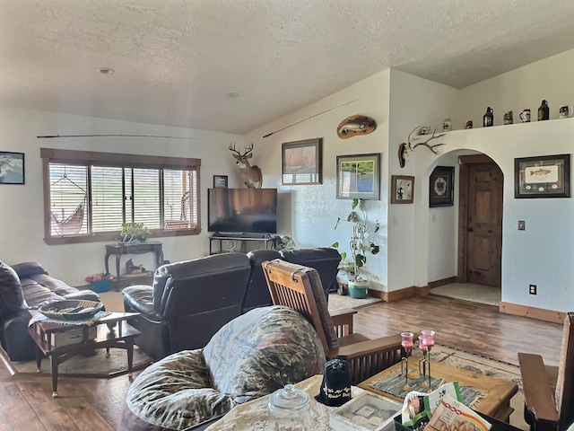 living room with arched walkways, lofted ceiling, a textured ceiling, and wood finished floors