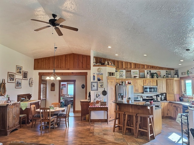 kitchen with lofted ceiling, a breakfast bar area, a center island, stainless steel appliances, and a textured ceiling