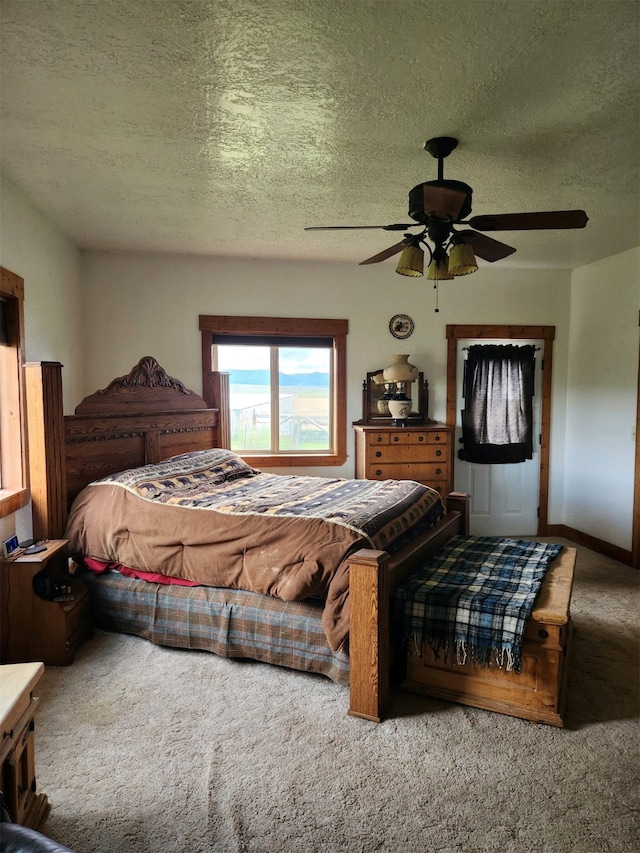 carpeted bedroom featuring a textured ceiling and a ceiling fan