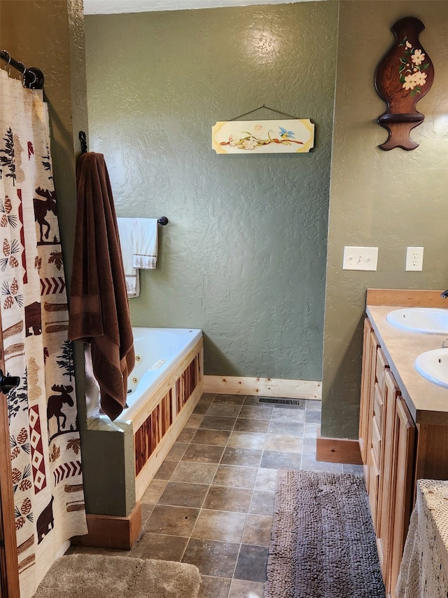 full bath featuring a bathtub, visible vents, a textured wall, a sink, and baseboards