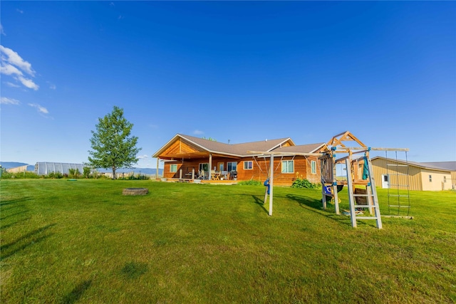 back of house featuring a lawn and a playground