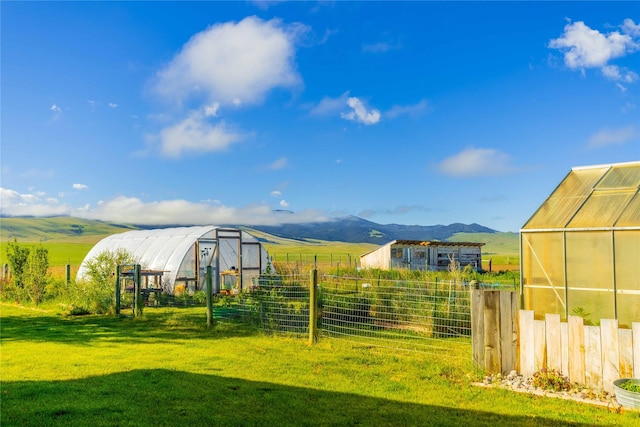 view of yard with a rural view, an outbuilding, fence, an exterior structure, and a mountain view