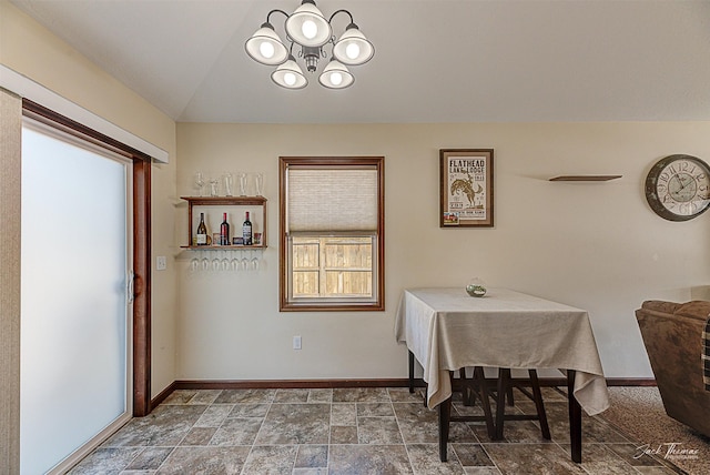 dining space featuring a chandelier, lofted ceiling, and baseboards