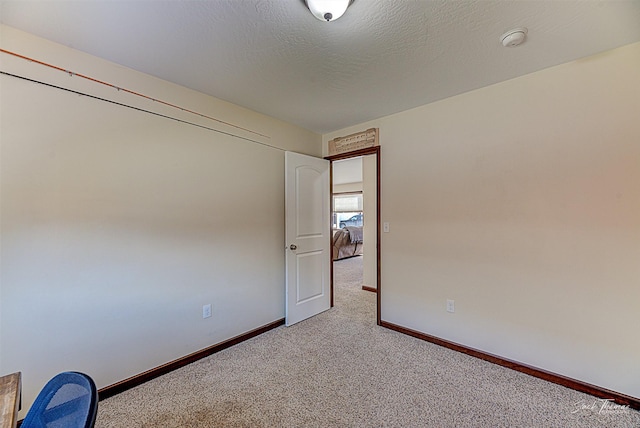 spare room with carpet, a textured ceiling, and baseboards