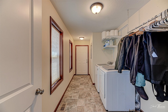 laundry room featuring a textured ceiling, washing machine and dryer, visible vents, baseboards, and stone finish floor