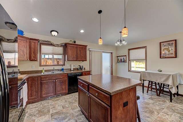 kitchen featuring dark countertops, a kitchen breakfast bar, a center island, hanging light fixtures, and black appliances