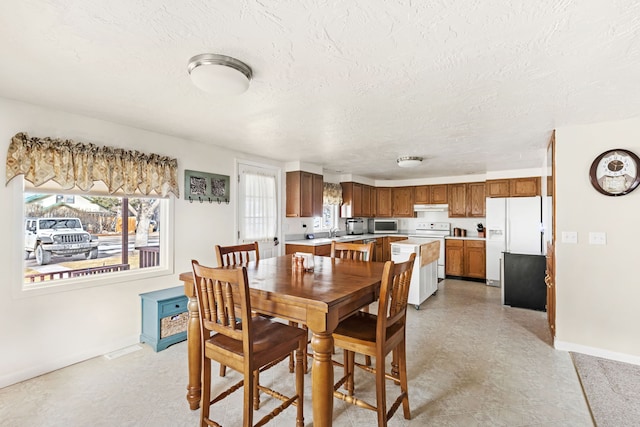 dining space with a textured ceiling and baseboards