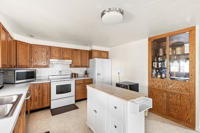 kitchen with stainless steel appliances, light countertops, brown cabinetry, and under cabinet range hood