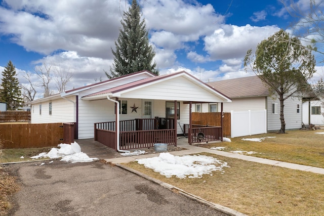 ranch-style house featuring covered porch, fence, and a front lawn