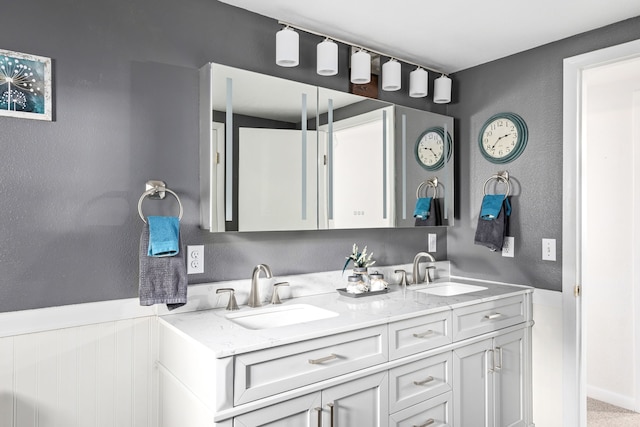 bathroom featuring a textured wall, a sink, and double vanity