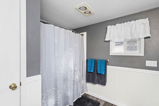 full bath featuring a shower with curtain, wood finished floors, and wainscoting