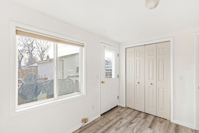 interior space featuring baseboards and light wood finished floors